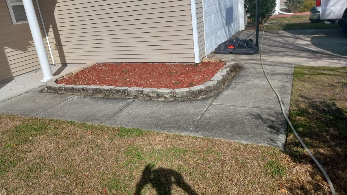 A shadow of a person is cast on a sidewalk in front of a house.