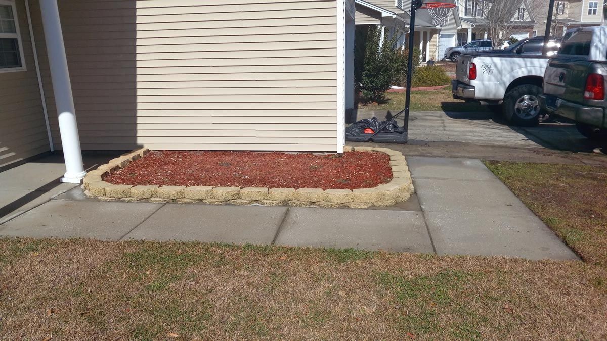 A concrete walkway leading to a house with a truck parked in front of it.