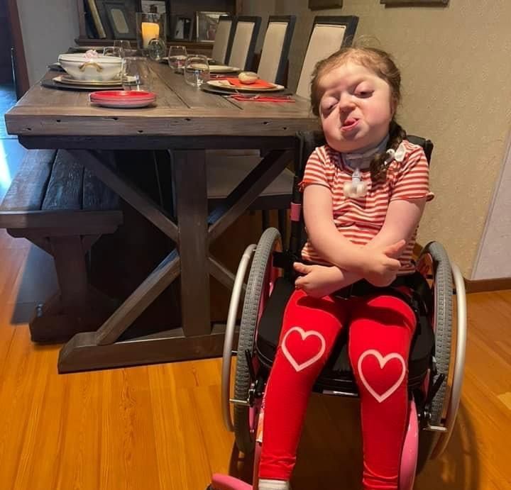 A little girl in a wheelchair with hearts on her pants