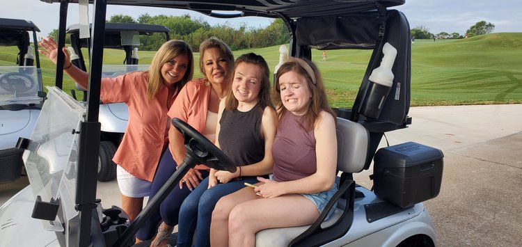 A group of young women are sitting in a golf cart.