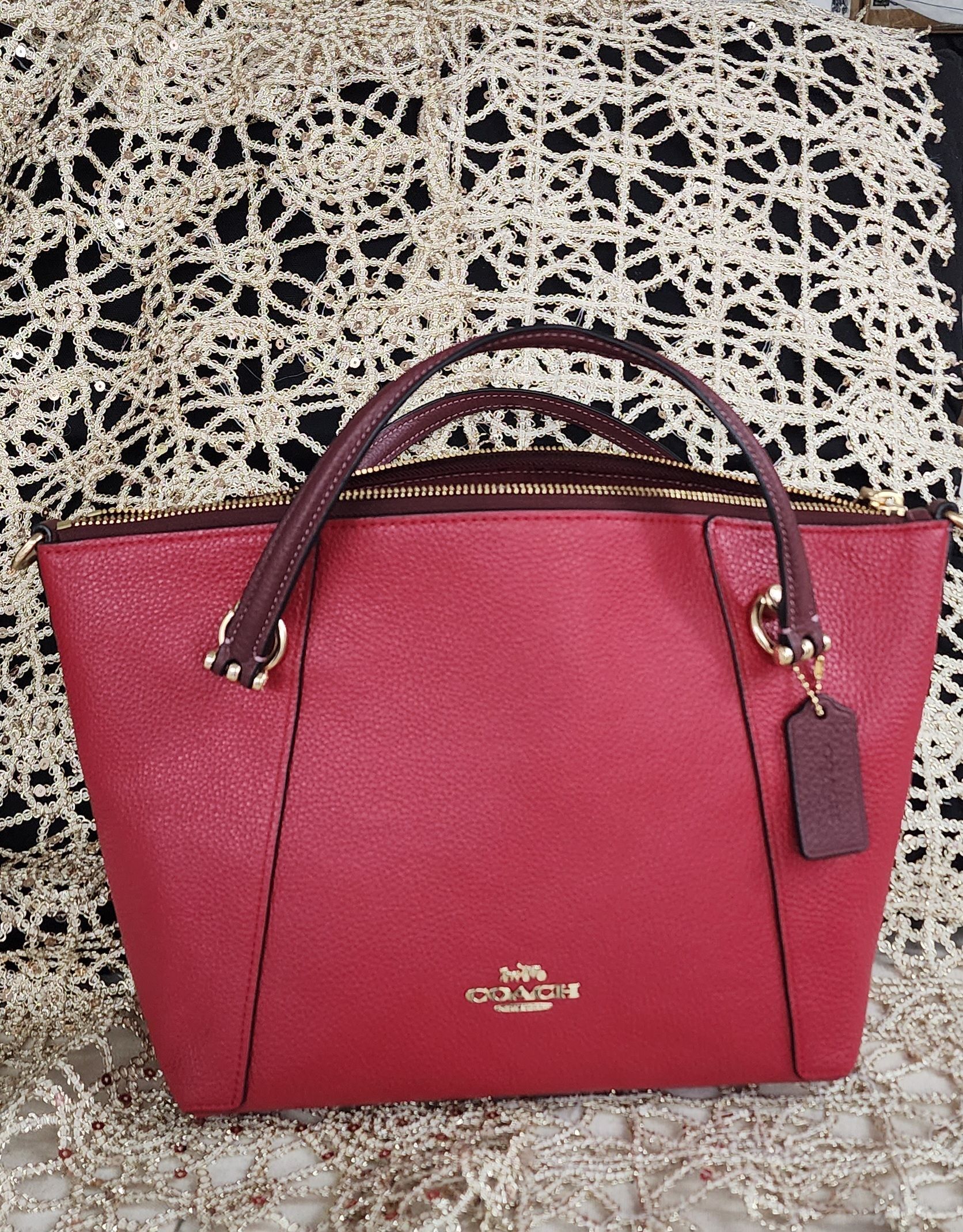 A red coach purse is sitting on a table.