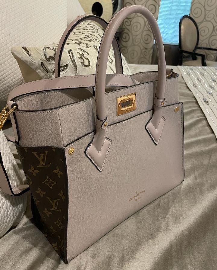 A louis vuitton bag is sitting on a bed.