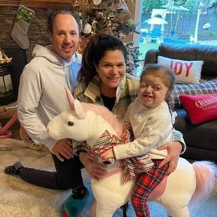 A family is posing for a picture with a stuffed unicorn.