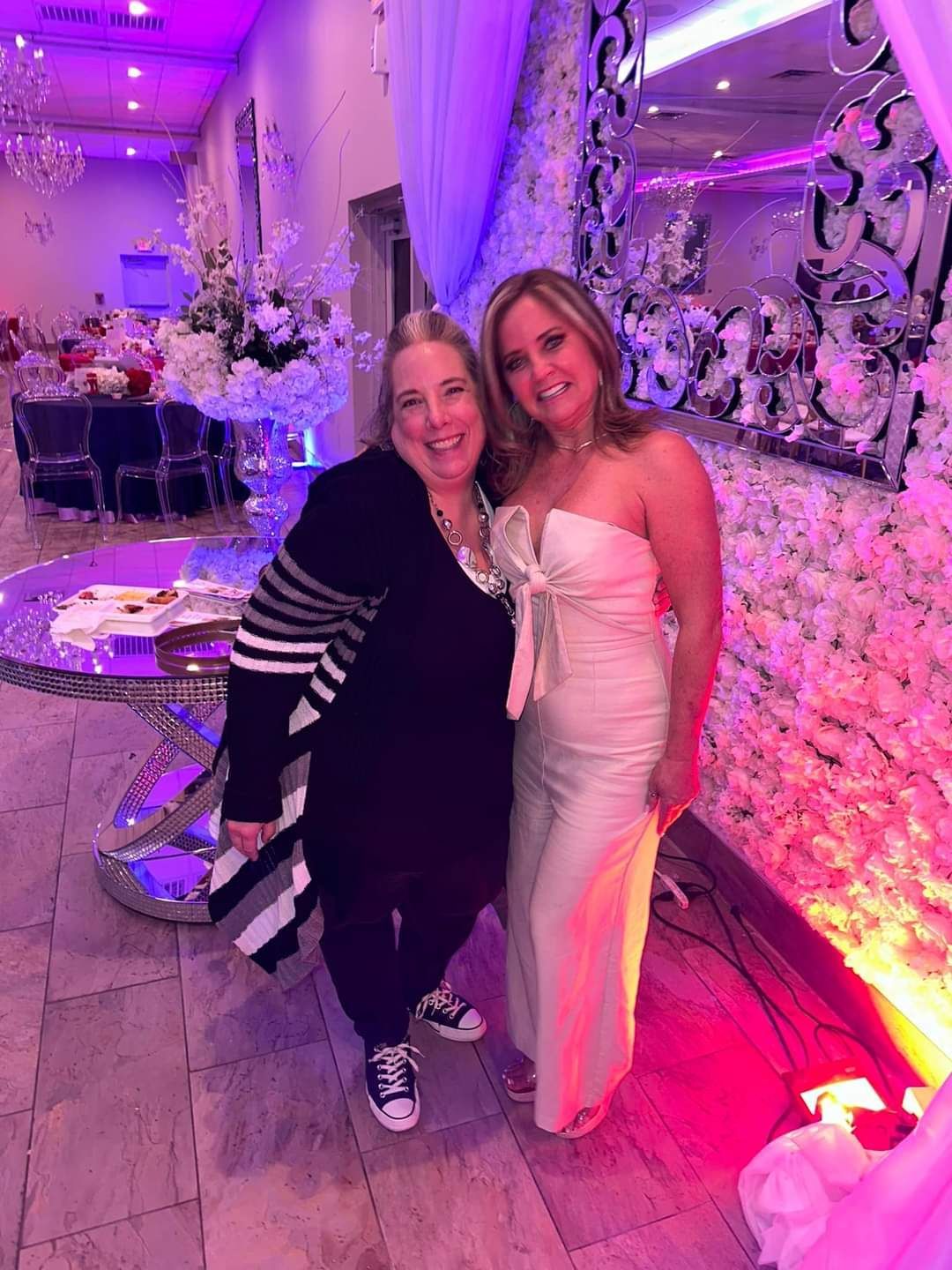 Two women are posing for a picture in a room with purple lights.