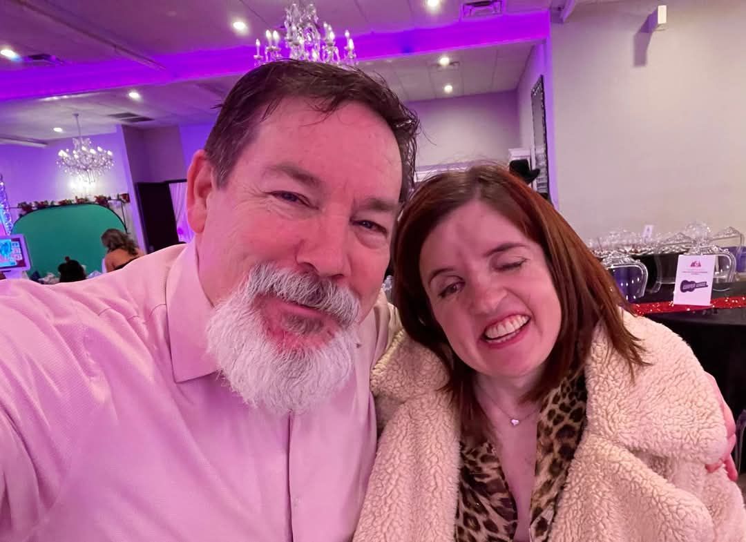A man and a woman are posing for a selfie in a room.