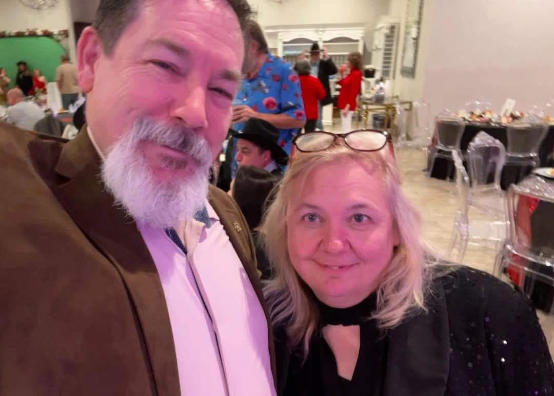 A man and a woman are posing for a picture in a room.