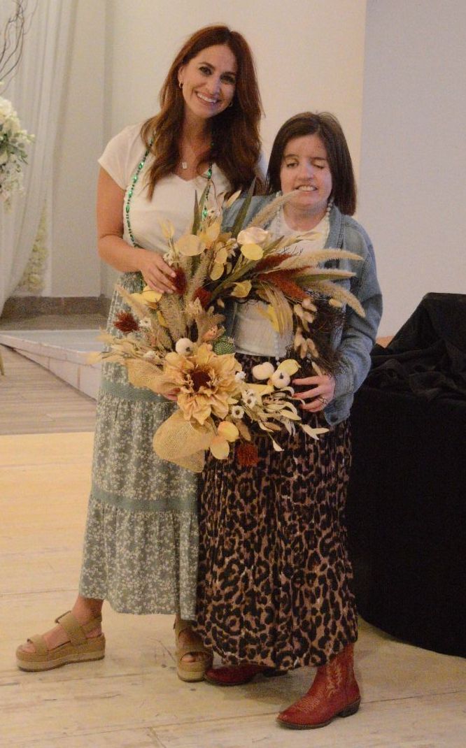 A woman and a girl are standing next to each other holding a bouquet of flowers.