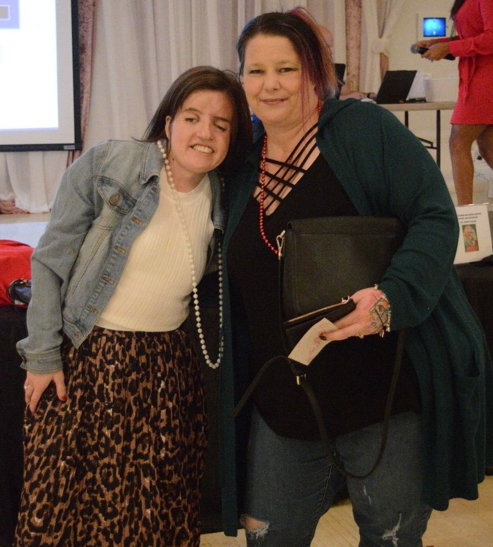 Two women posing for a picture in front of a projector screen