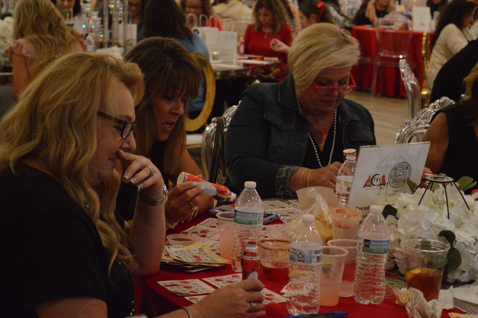 A group of women are sitting at a table playing bingo.