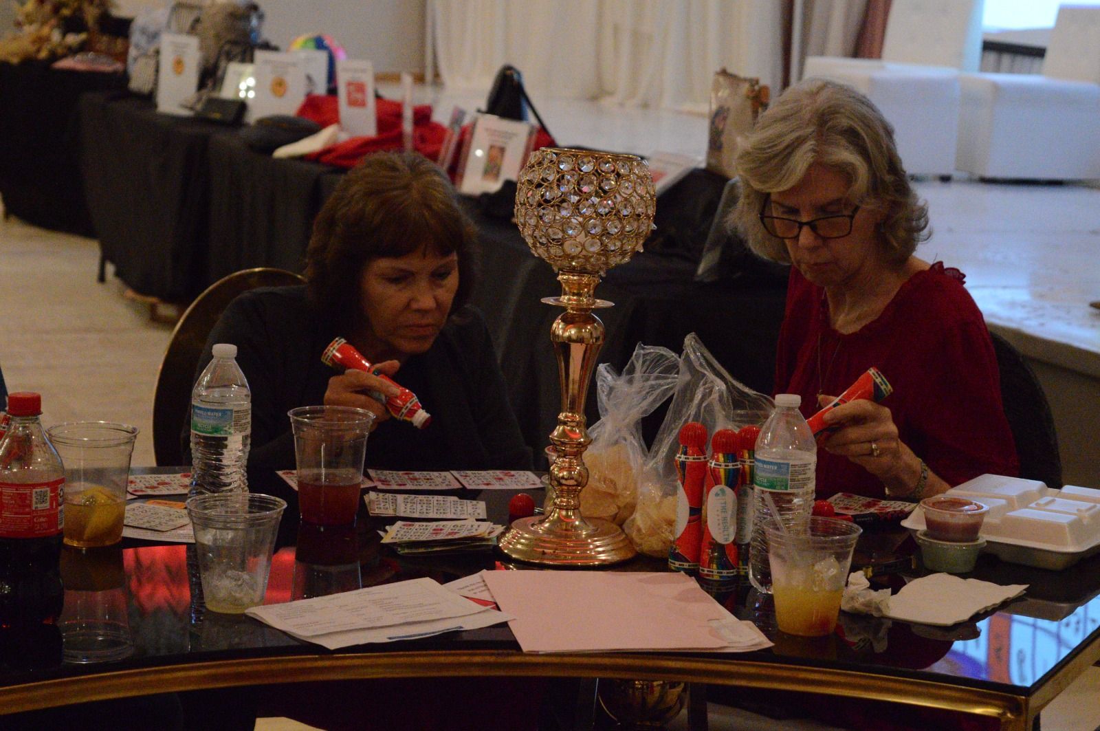 Two women are sitting at a table playing bingo
