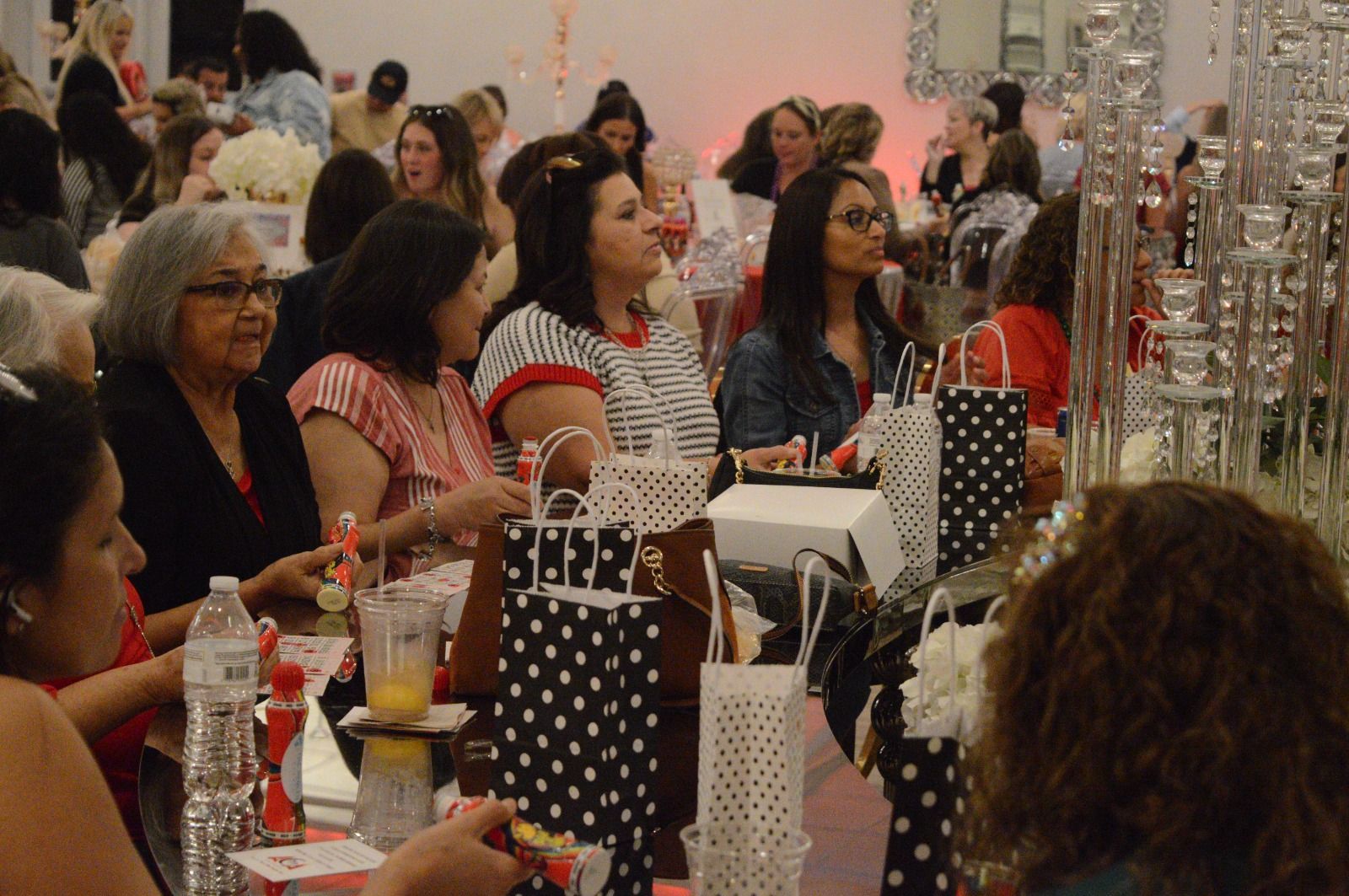 A group of women are sitting at a table with polka dot bags on it