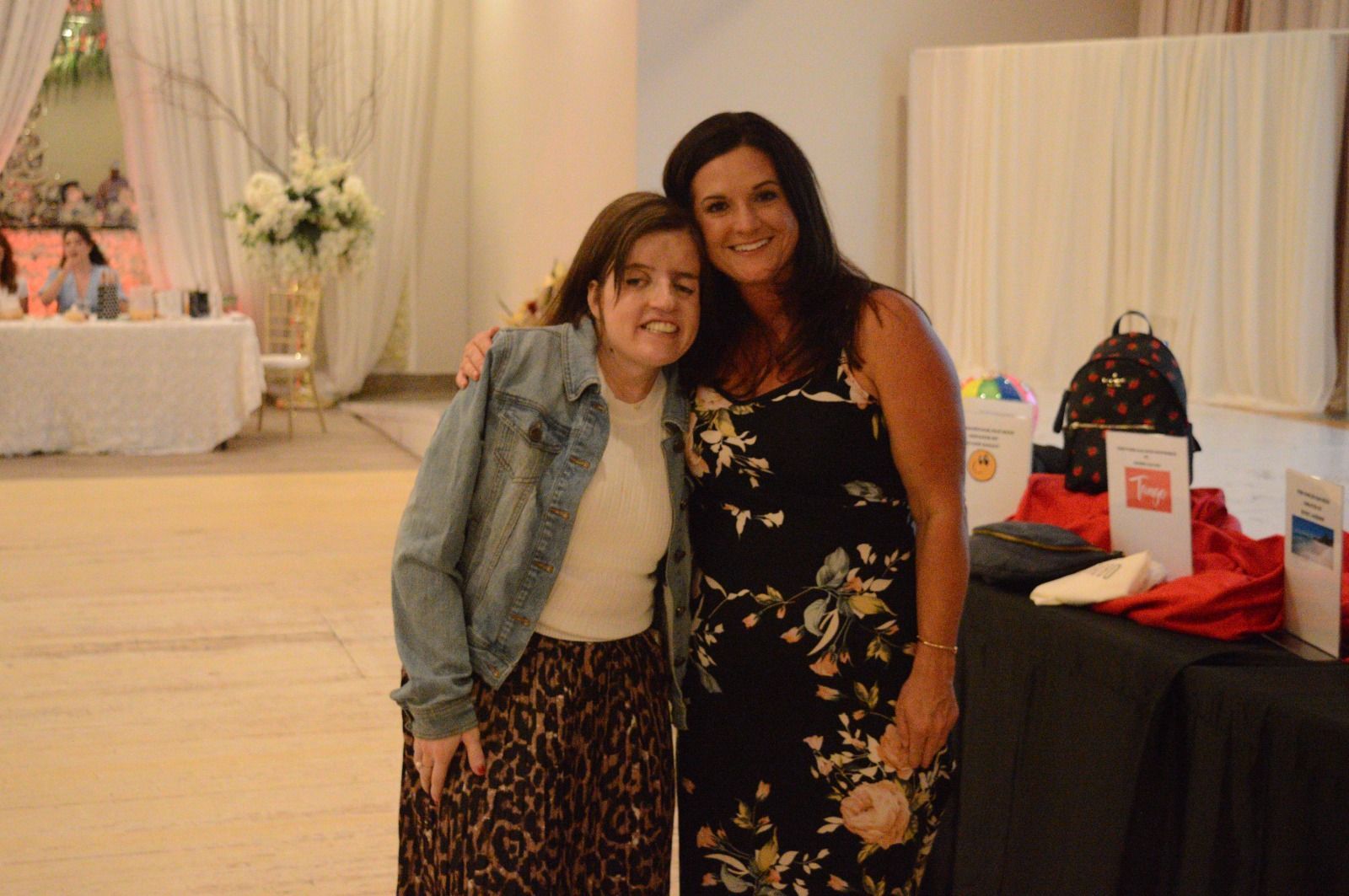 Two women are posing for a picture together in a room.
