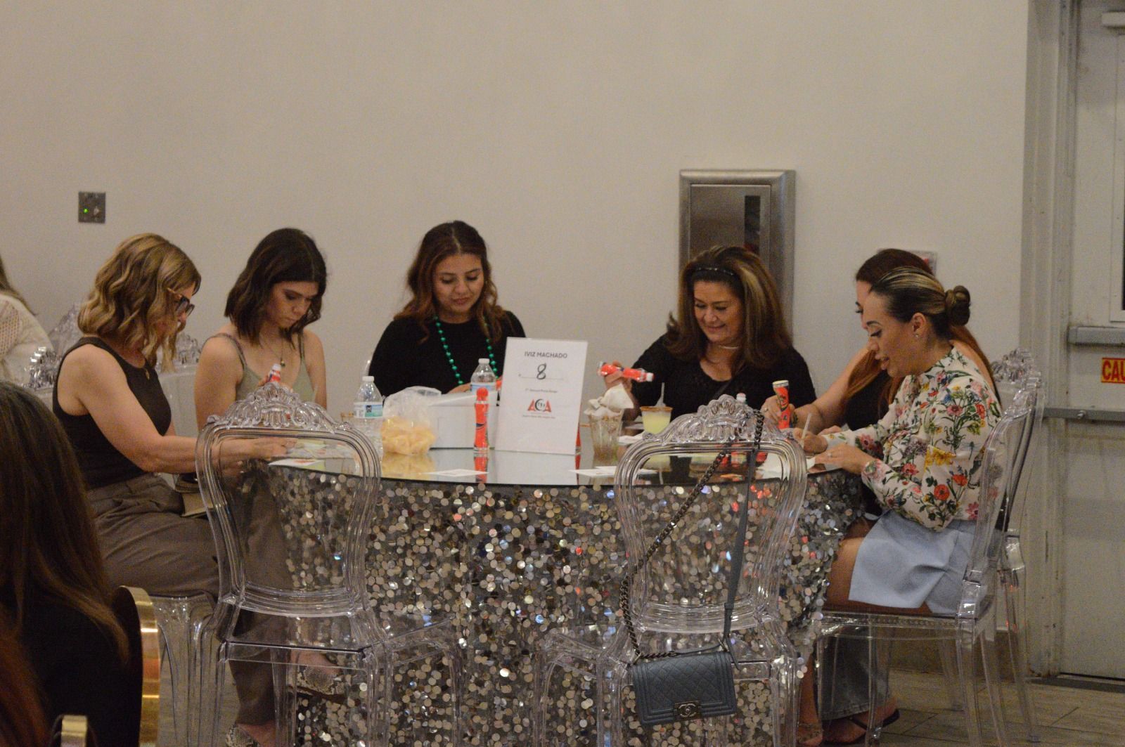 A group of women are sitting around a table in a room.
