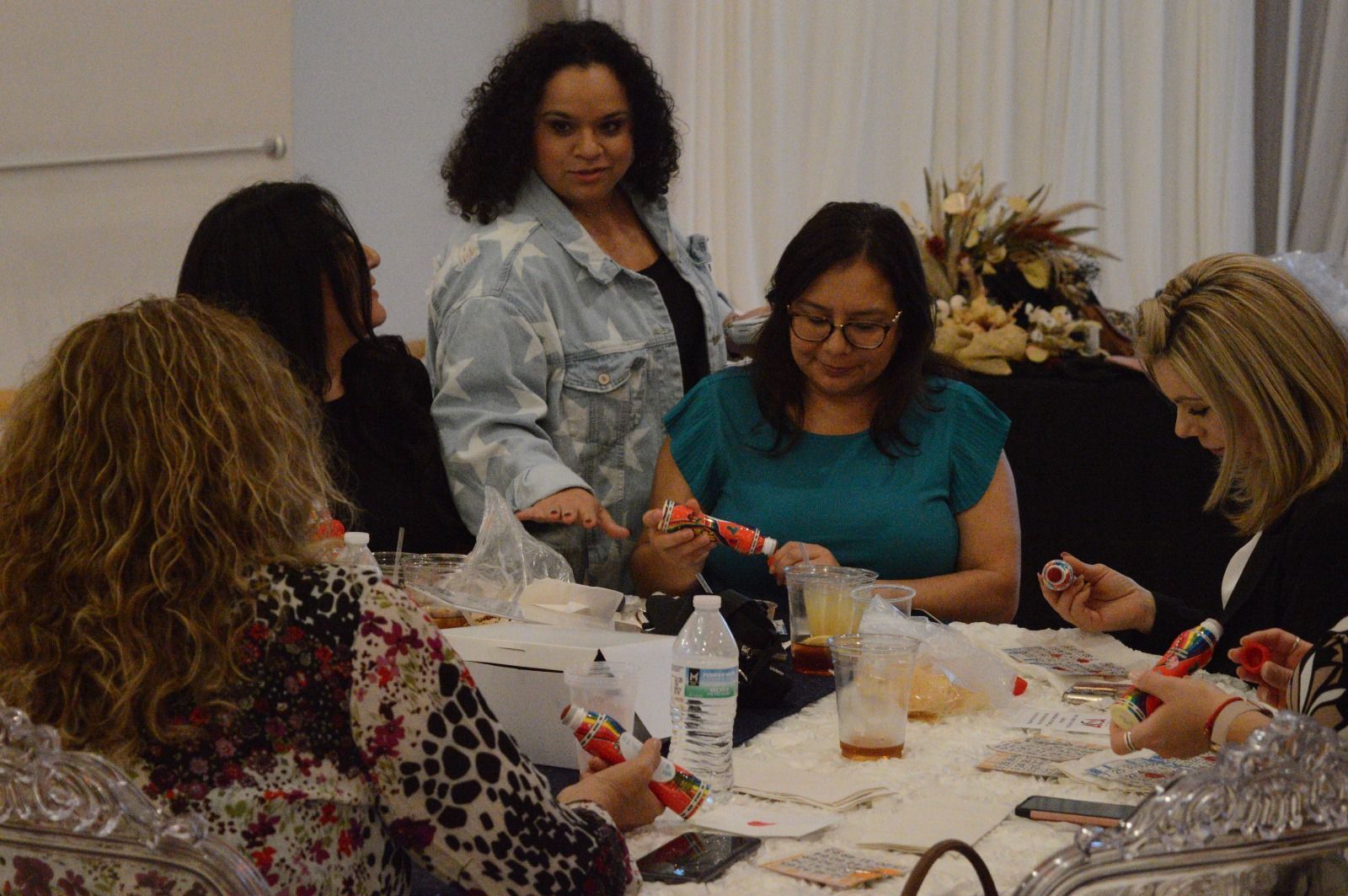 A group of women are sitting around a table making crafts