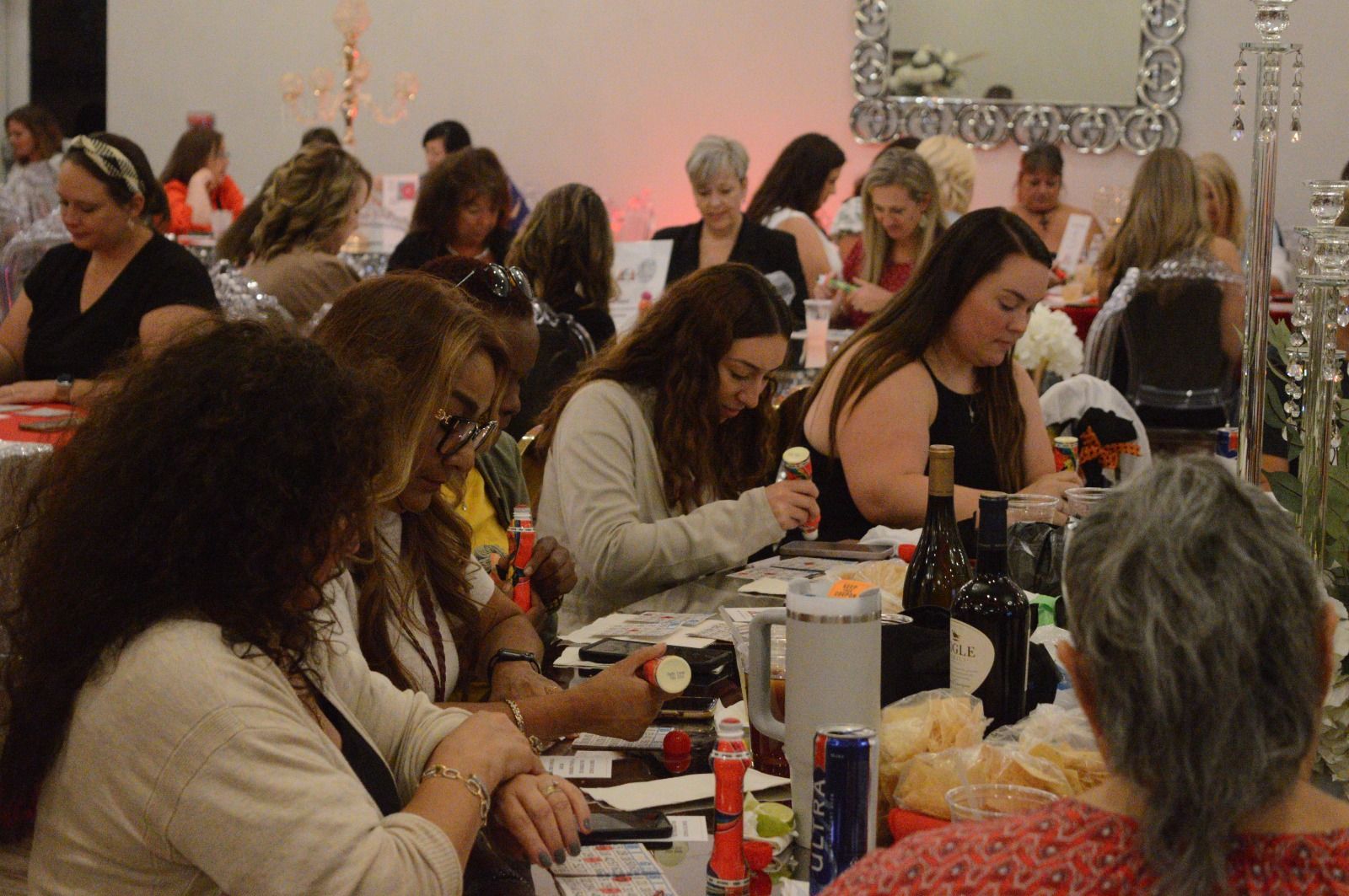 A group of women are sitting at a table with bottles of wine.