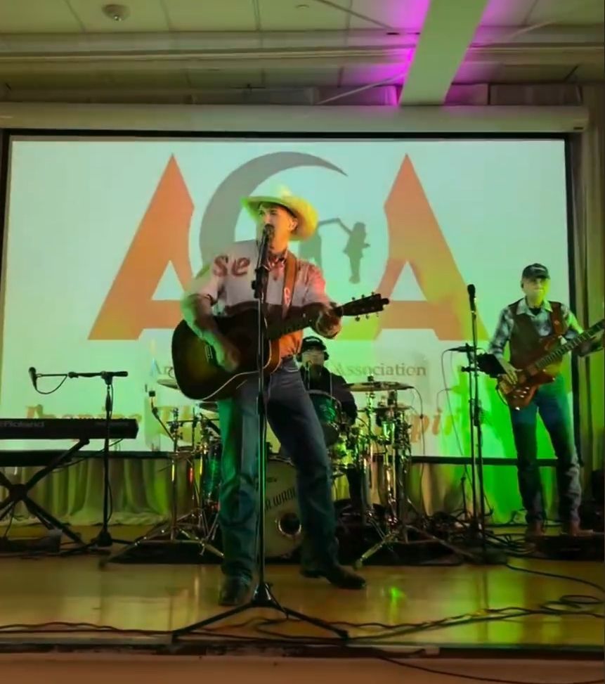 A man singing into a microphone while playing a guitar