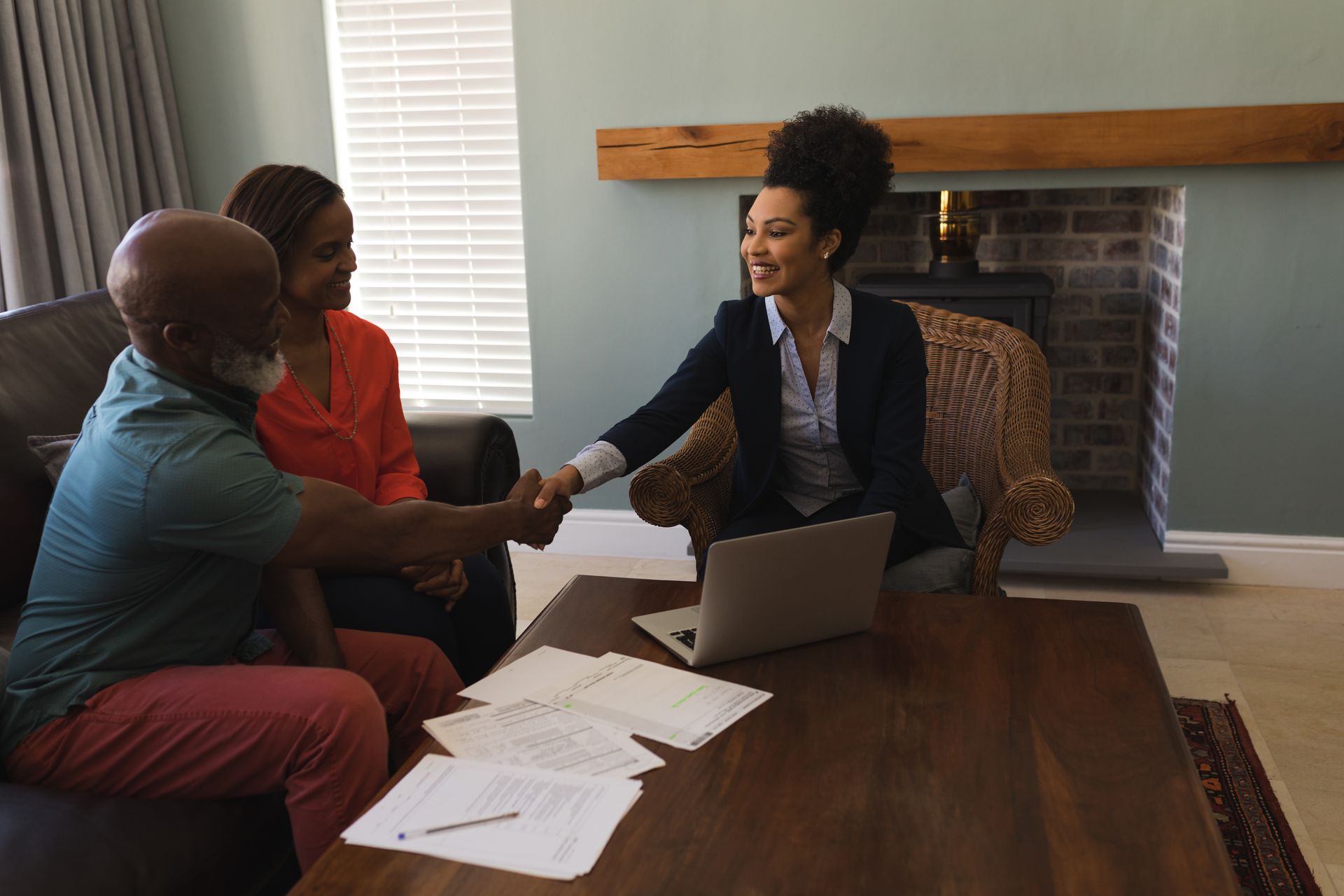 A woman is shaking hands with a man and woman in a living room.