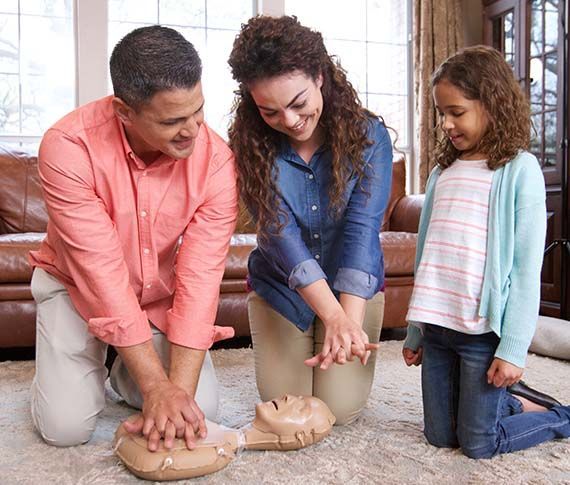 Three people knead dough on a kitchen counter, smiling in a bright home kitchen.