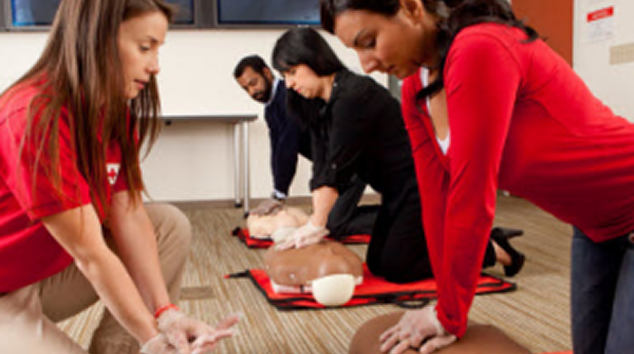 People practicing CPR on a training manikin in a classroom setting