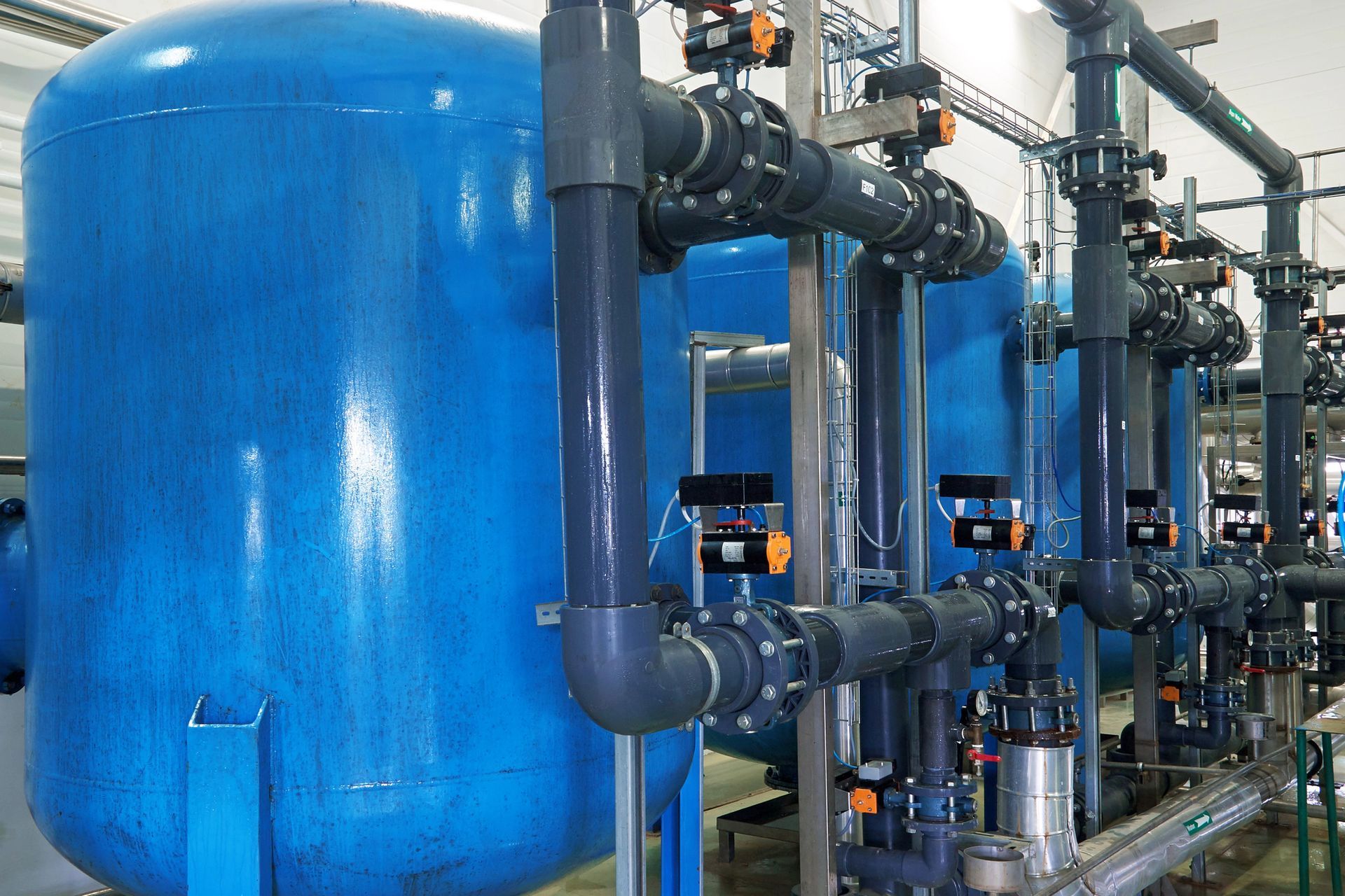 Serbatoi di filtrazione dell'acqua blu e tubi collegati in un ambiente industriale.