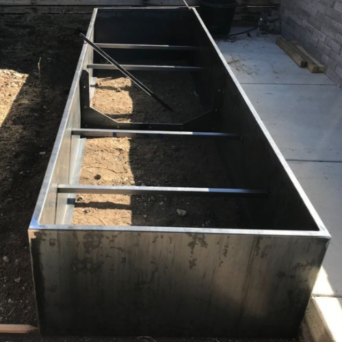 A large metal planter with a shovel in it
