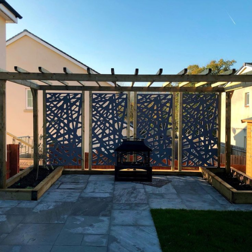 A patio with a pergola and a grill in front of a house