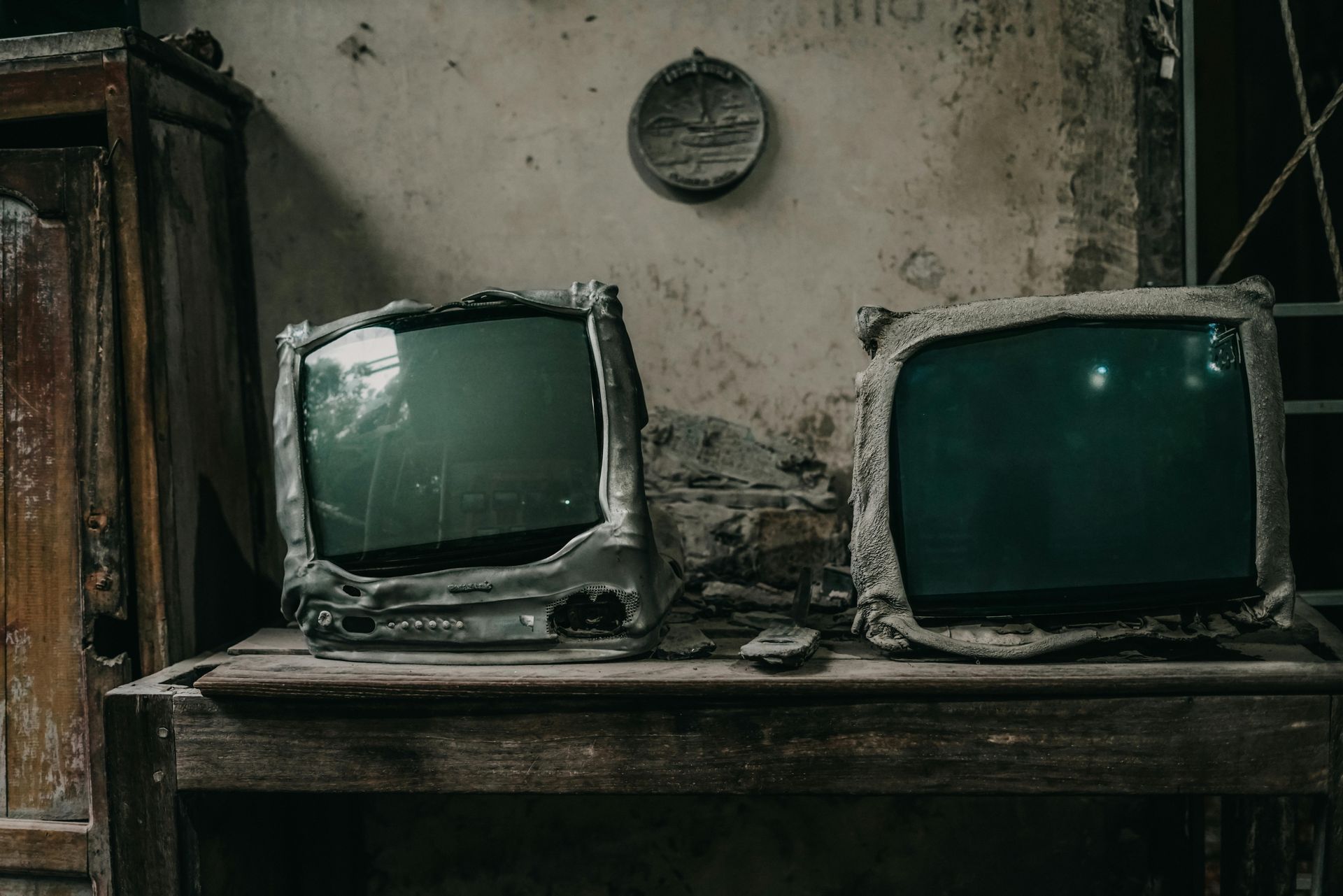 Two old televisions are sitting on a wooden table.