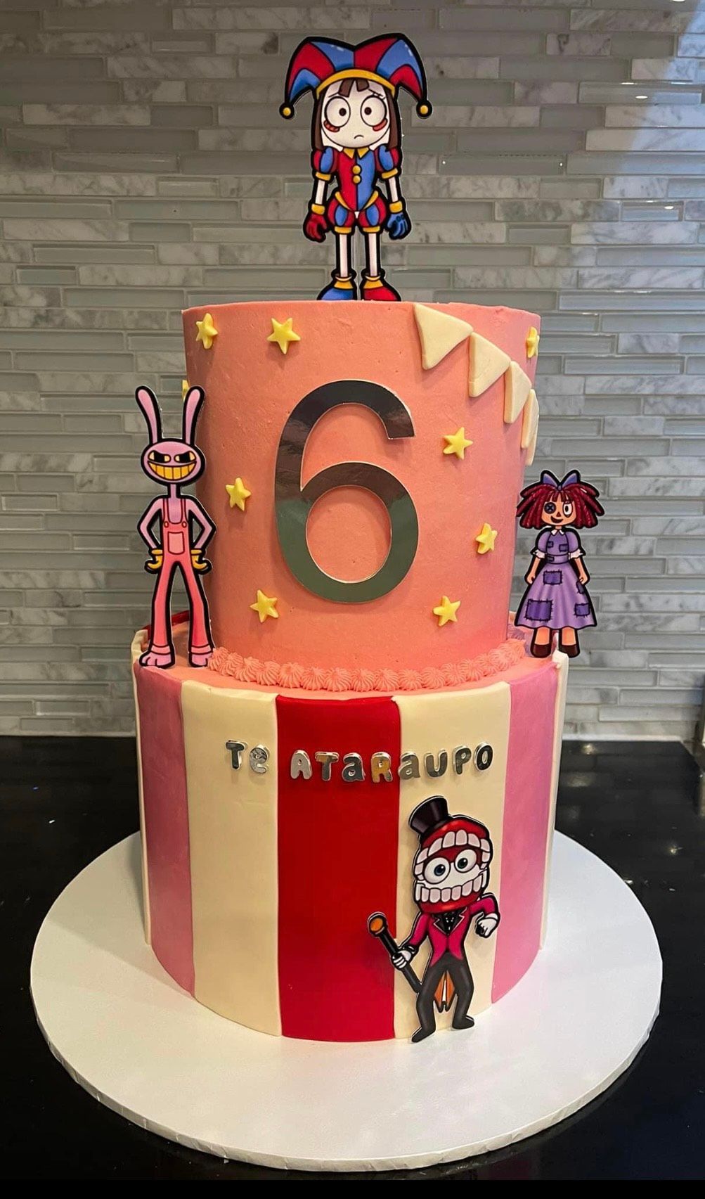 A pink and white cake with a number 6 on top of it.