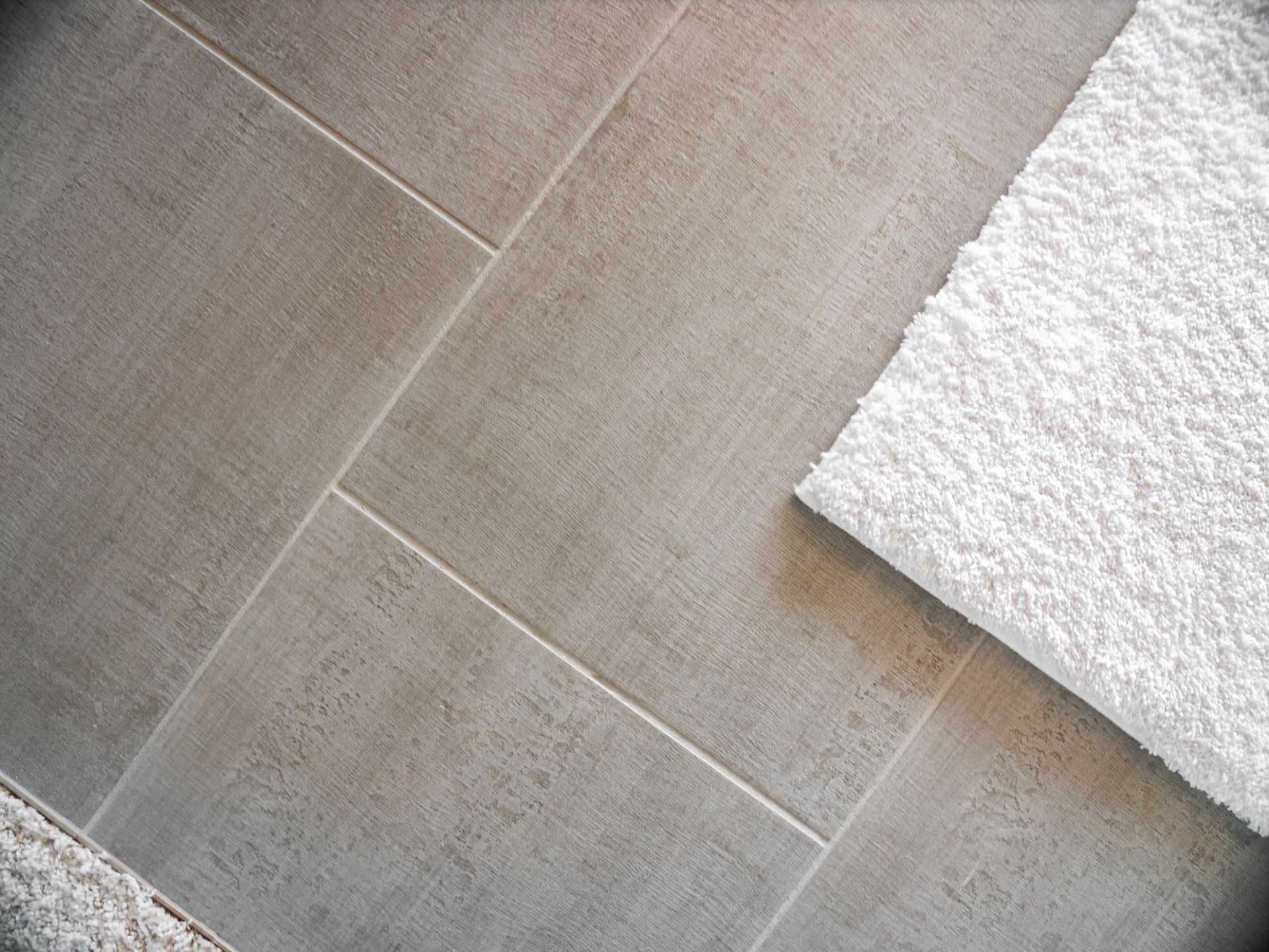 Gray tiled floor with white towel partially visible.