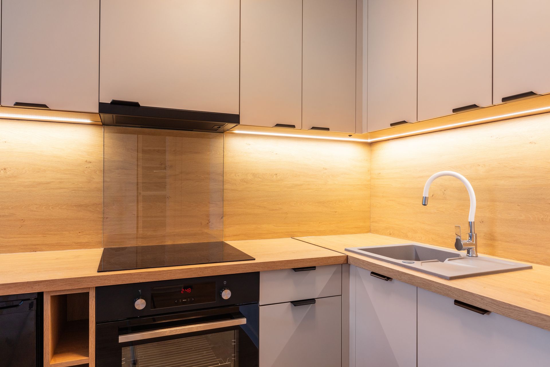 Modern kitchen corner with light wood countertops, white cabinets, and built-in appliances.
