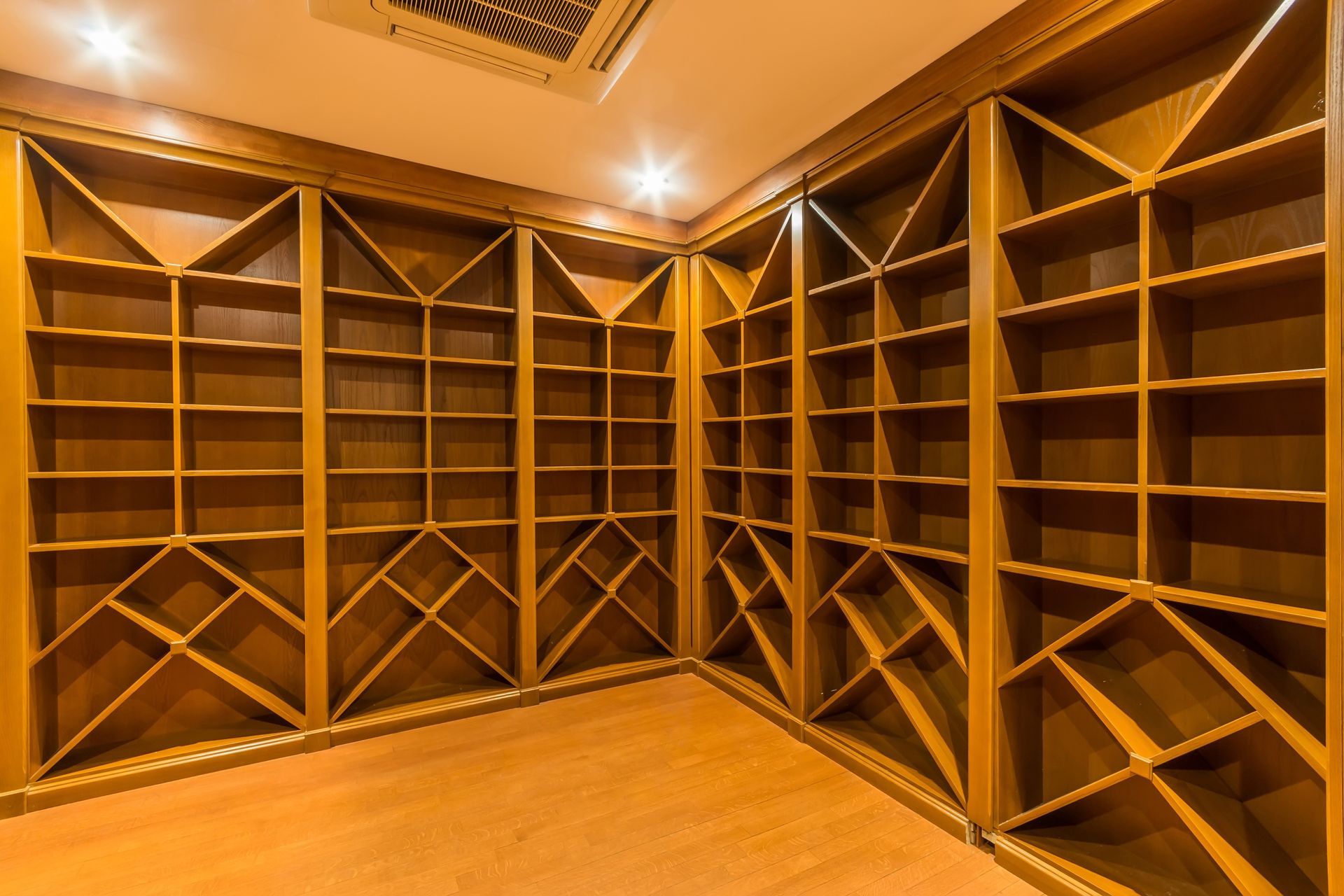 Empty wooden wine rack built into a room's corner with light wood floors.