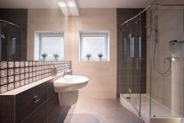 Glass shower enclosure in a updated bathroom with a tan and brow interior decorated color.