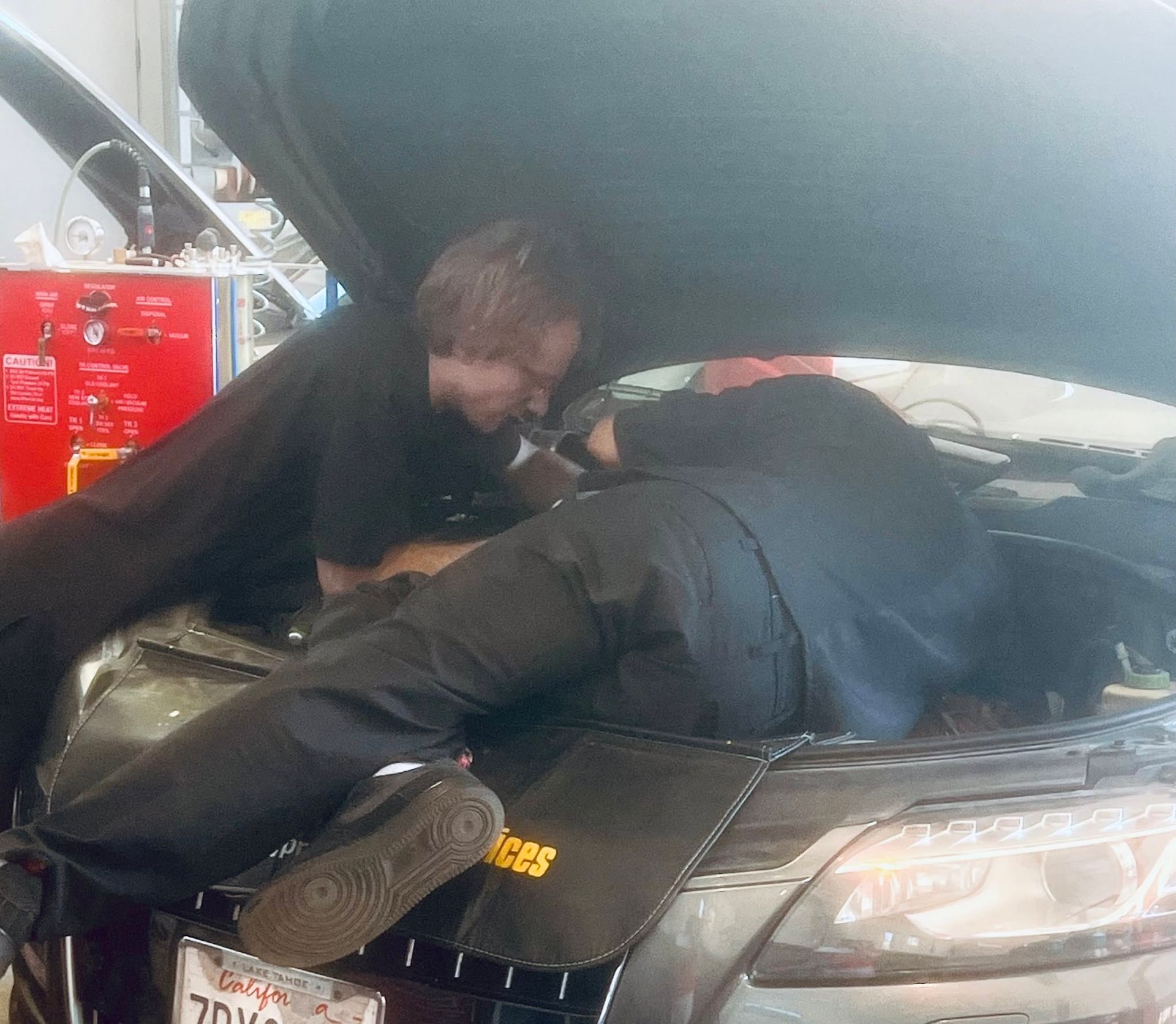 Technicians Working Under An Open Vehicle Hood | German Import Garage