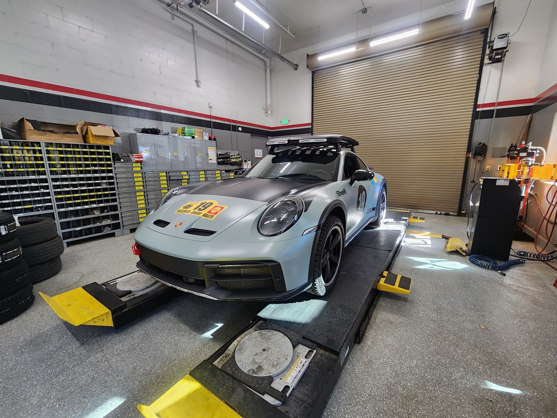 Silver Porsche On A Vehicle Lift Inside The Workshop | German Import Garage