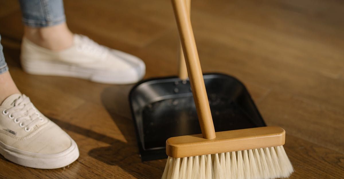 A person is sweeping the floor with a broom and dustpan.