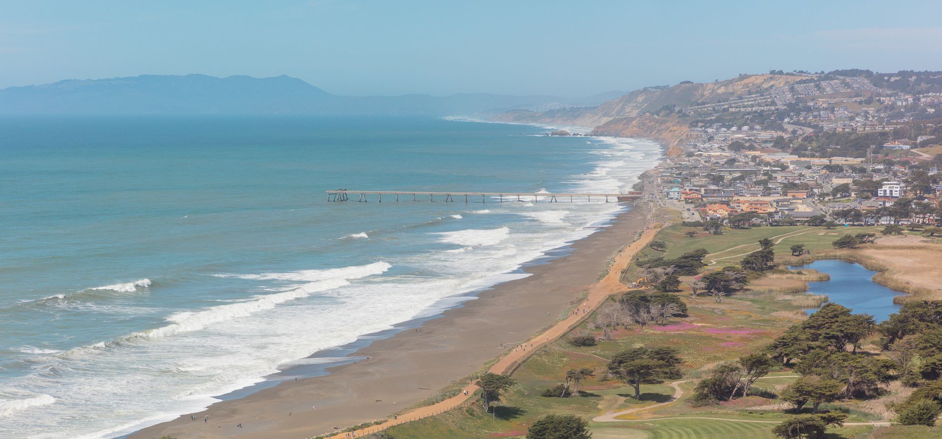 An aerial view of a beach with a city in the background.
