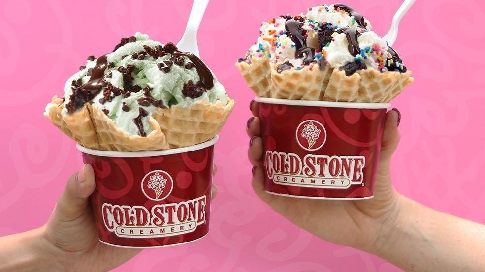 A person is holding two cups of cold stone ice cream