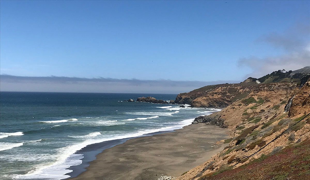 A view of a beach from a cliff overlooking the ocean.