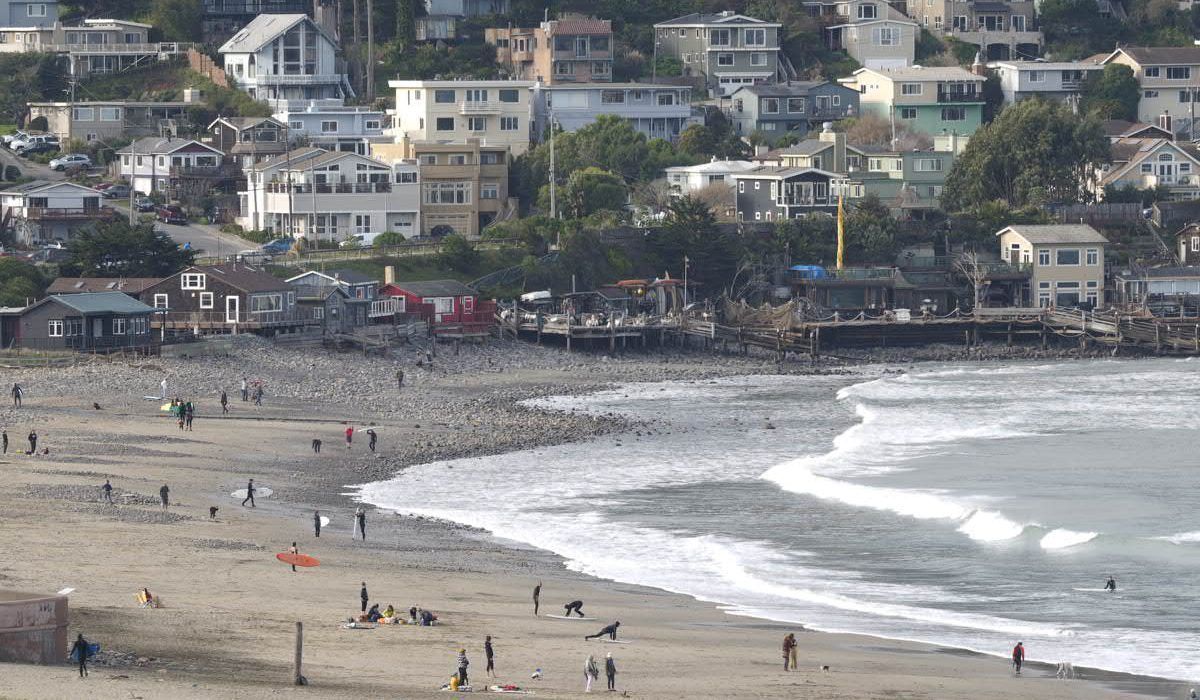 A beach with a lot of people and buildings in the background