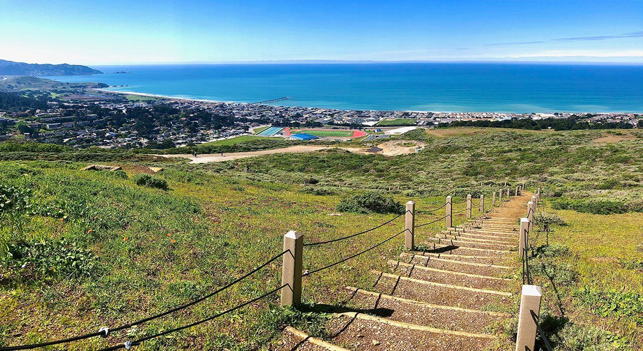A set of stairs leading up to a hill overlooking the ocean.