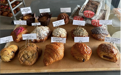 A wooden table topped with a variety of pastries and muffins.