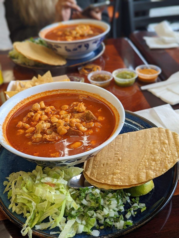 A bowl of soup and a plate of food on a table.