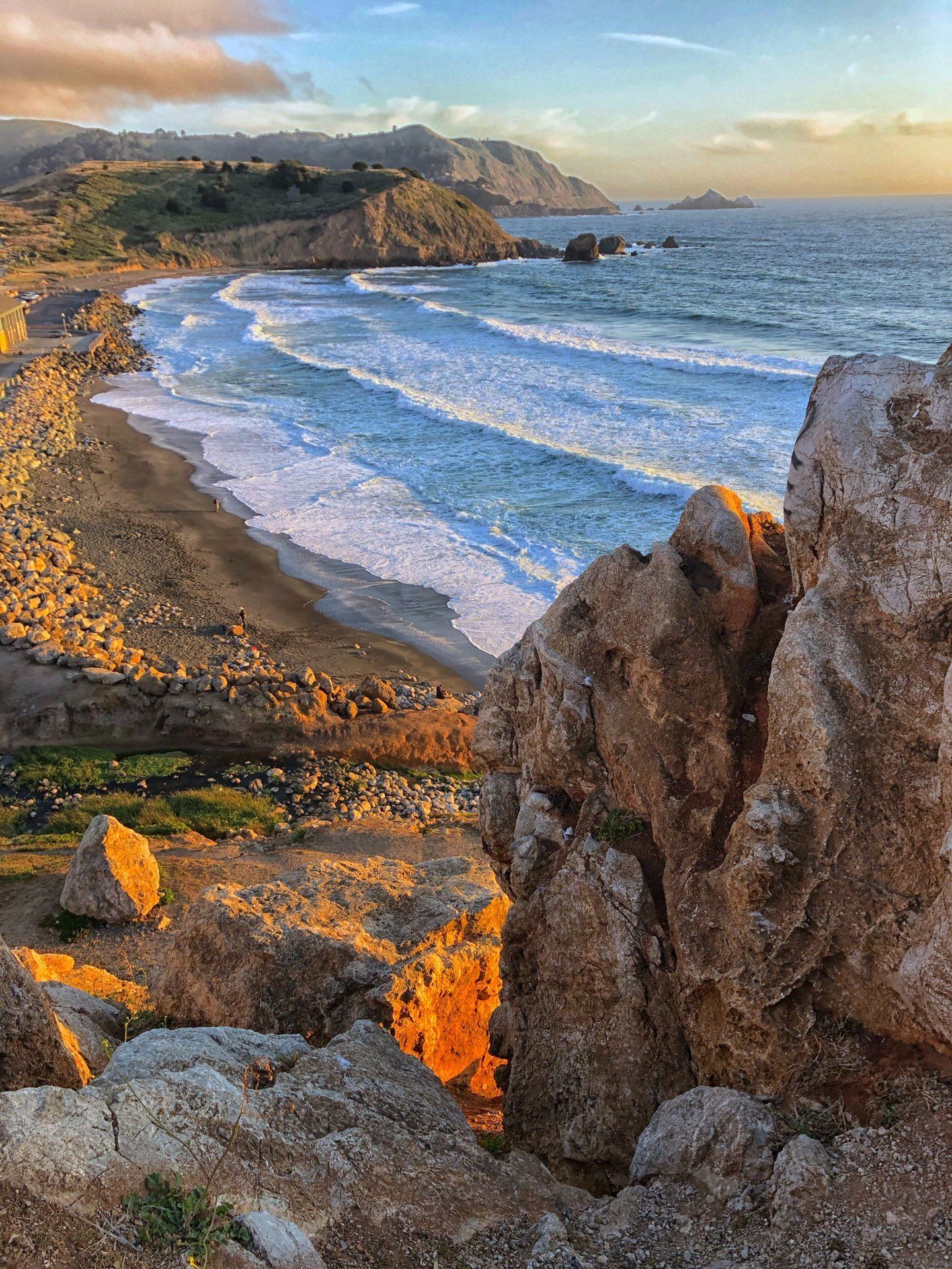 A view of a beach from a rocky cliff overlooking the ocean.