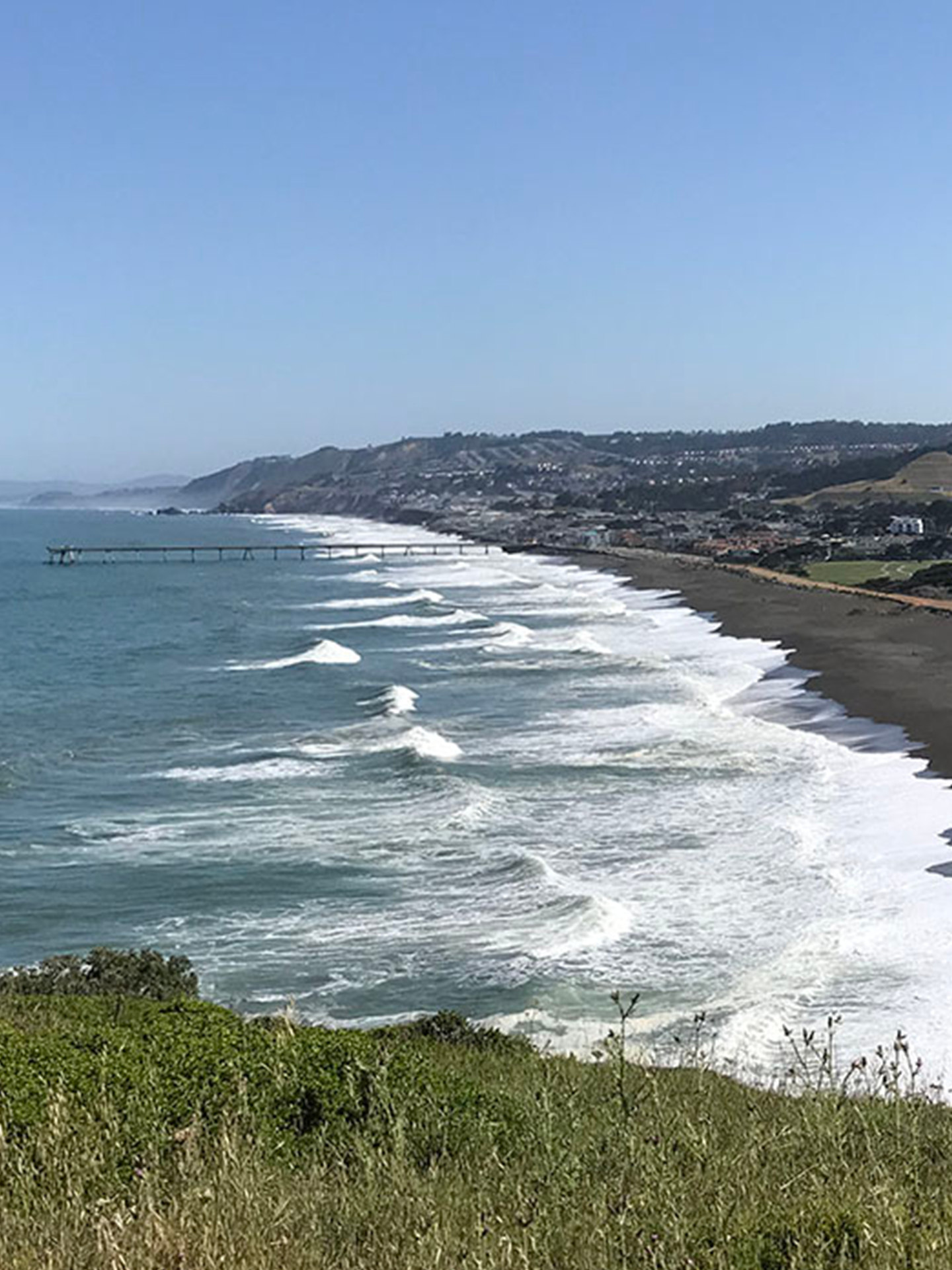 A view of a beach with waves crashing on the shore