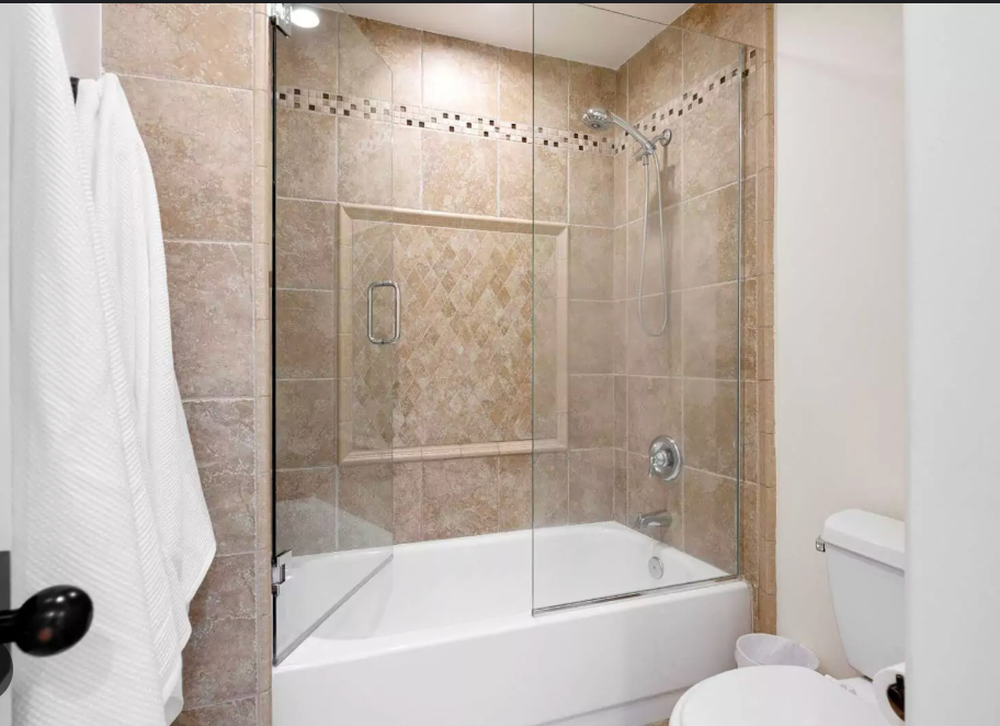 Luxurious bathroom with a marble-tiled shower, glass doors, and gold fixtures.