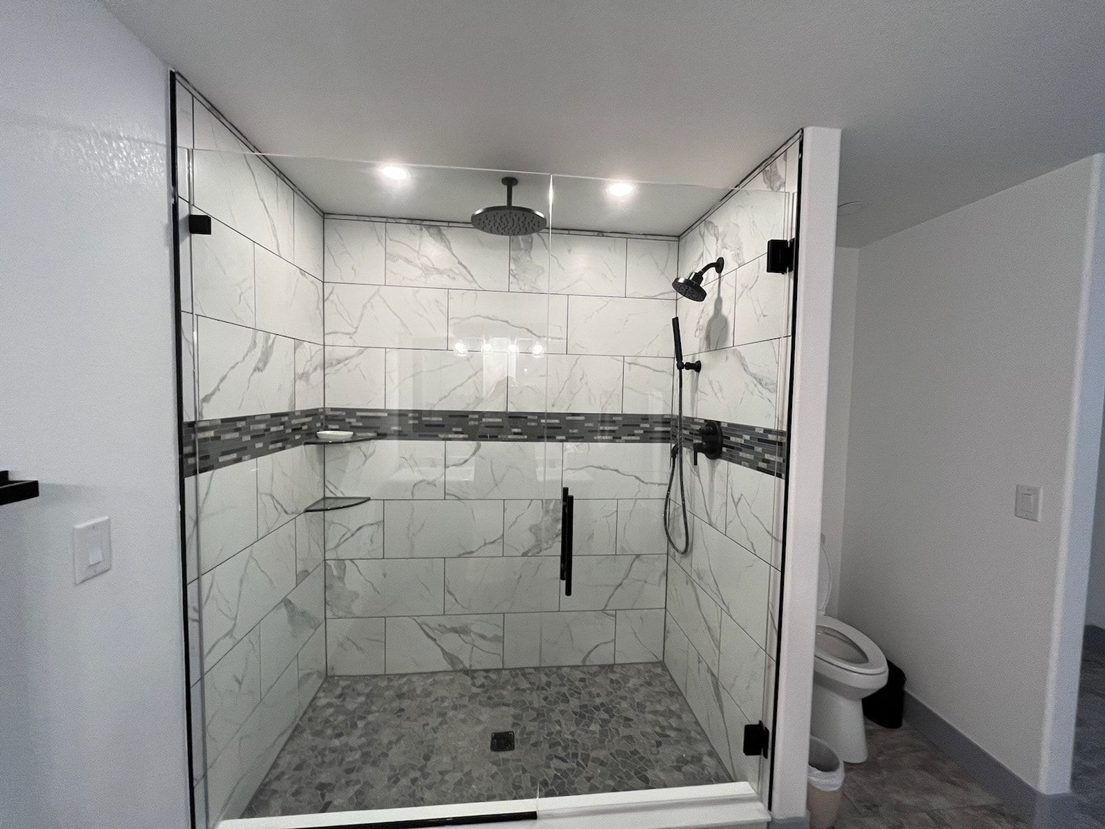 Modern glass shower with marble tile and hexagon floor in a bright bathroom