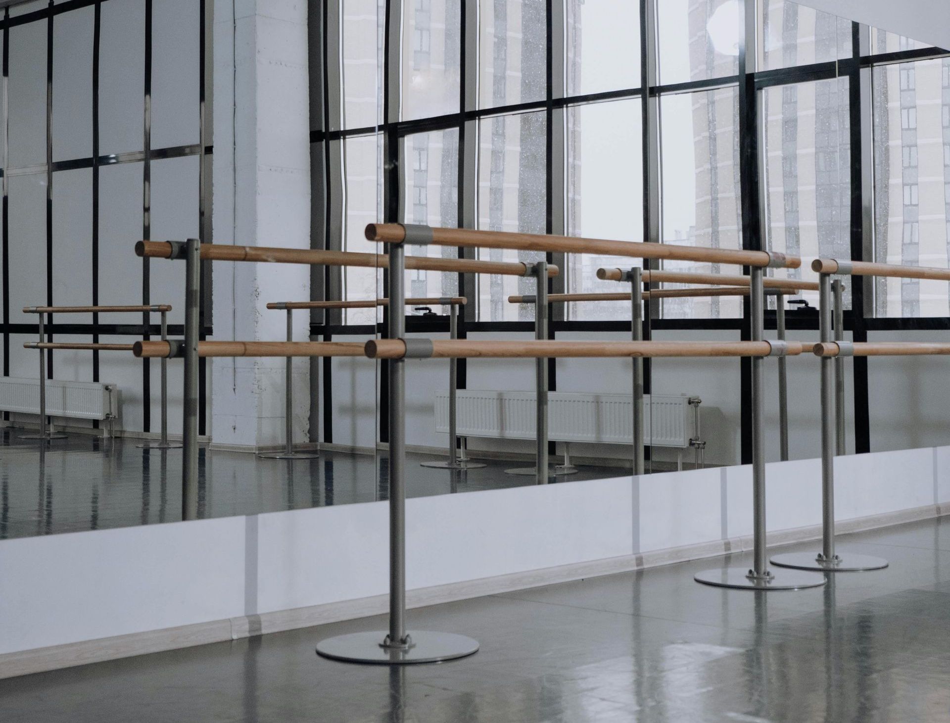 Dance studio interior: mirrors, ballet barres, large windows overlooking cityscape.