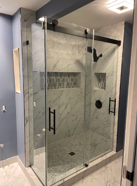 Colorado Glass and Mirror installer fitting a frameless shower door panel in a Denver bathroom