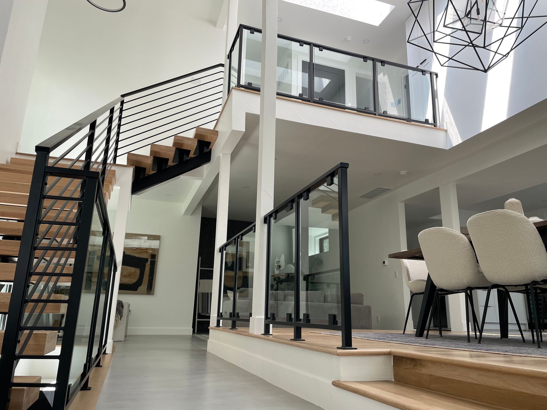 Bright modern home interior with staircase, glass doors, and dining area under high ceilings