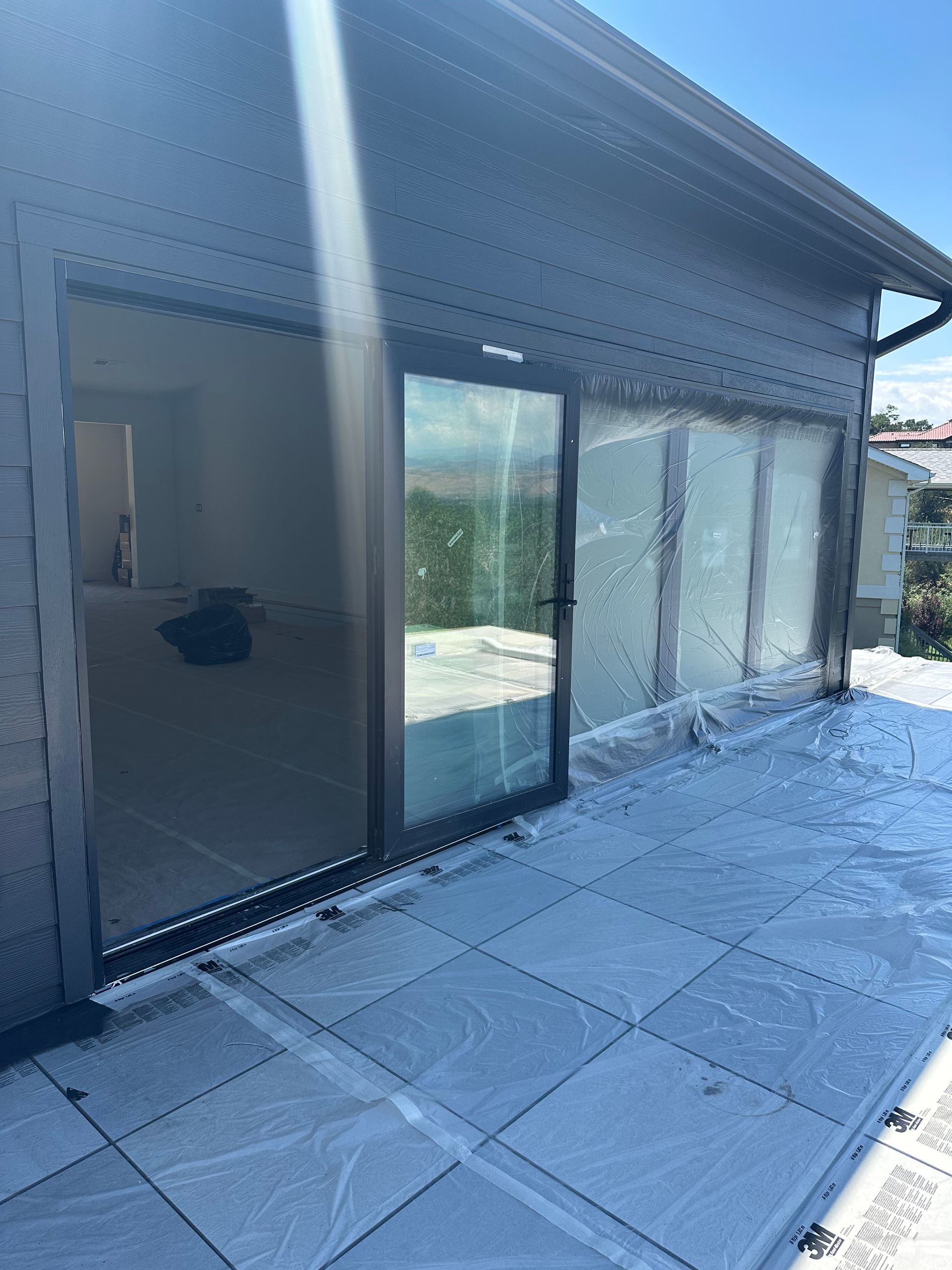 Exterior of a building with a glass door and patio. Grey tiles cover the patio floor.